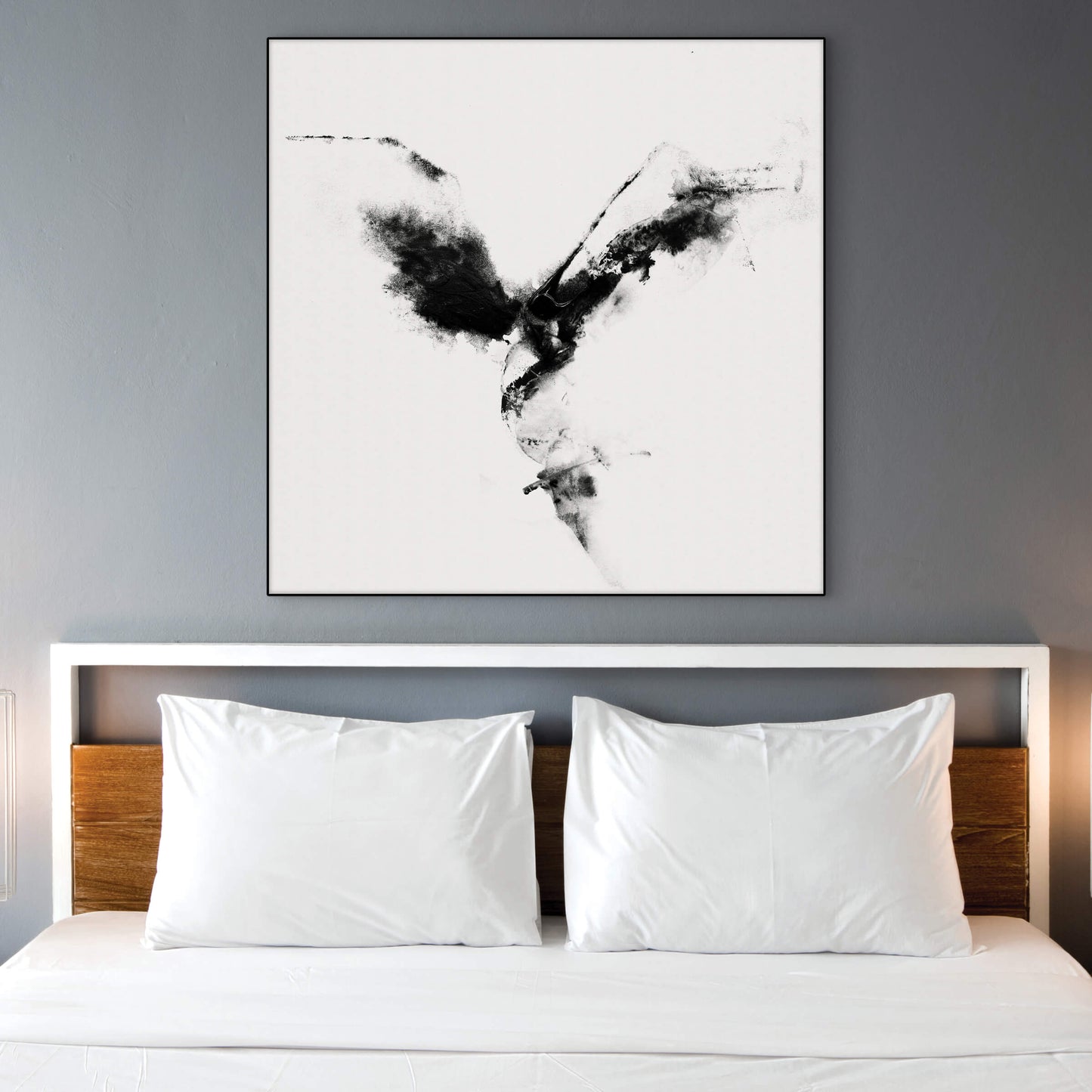 Extra large black and white abstract wall art hangs above white bed on light gray wall.