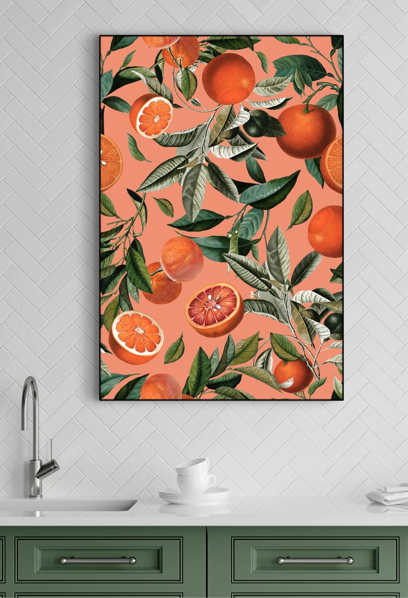 Large vertical orange fruit print hangs on white tile wall in kitchen above sink.