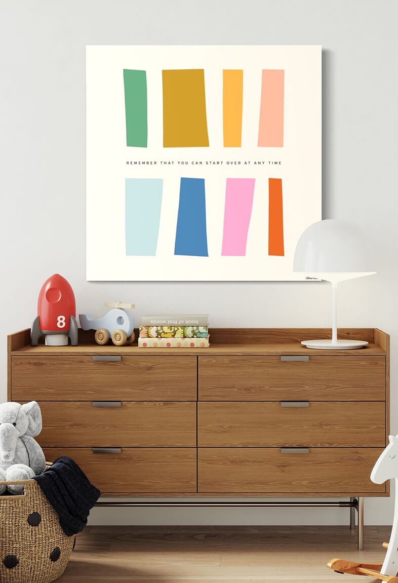 Huge colorful minimalist wall art featuring various sized rectangles with the quote "remember that you can start over at any time" hangs on white wall above changing table in modern nursery.