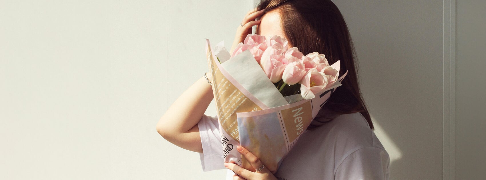 Woman holding a bouquet of flowers in front of her face for Valentine’s Day