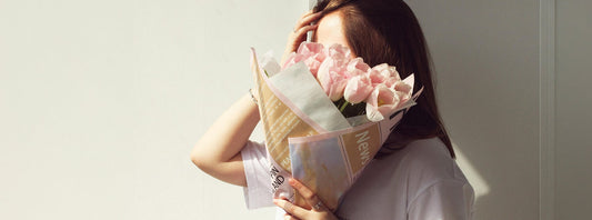Woman holding a bouquet of flowers in front of her face for Valentine’s Day