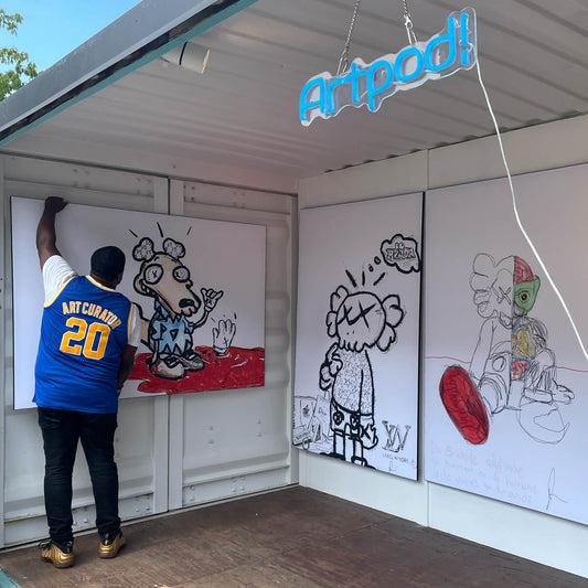 Artist Stephen Smith hangs his ArtPrize 2022 entry "Ugly Clothes" which are 3 digitally drawn characters in black and white printed on BIG Wall Décor in His Art Pod