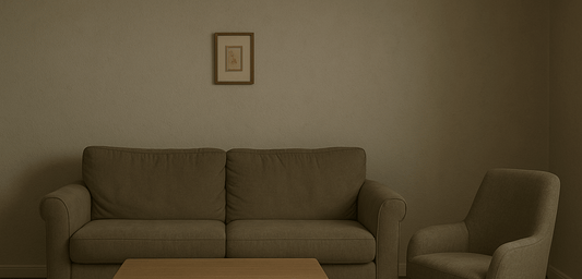 Dim neutral living room with dull beige furniture and a small framed artwork on the wall.