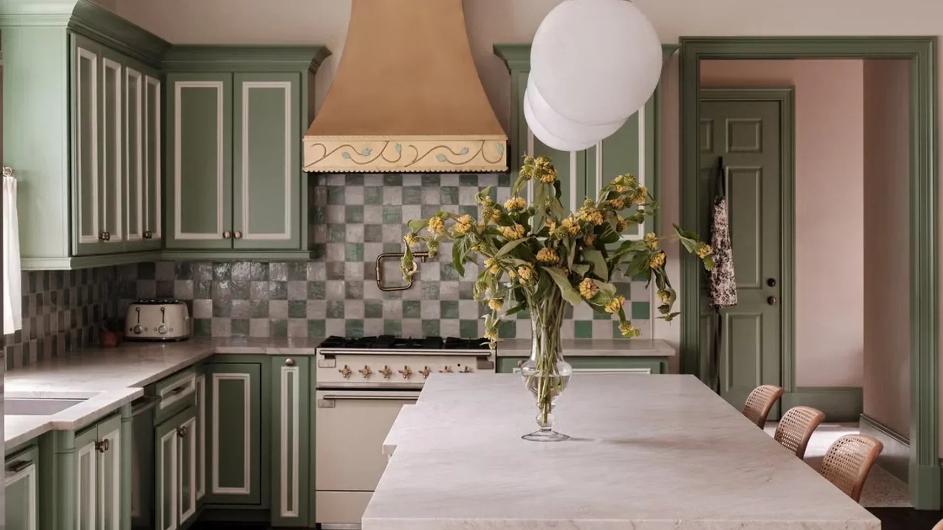trendy modern kitchen with sage cabinetry and a sage and white tile backsplash with copper accents