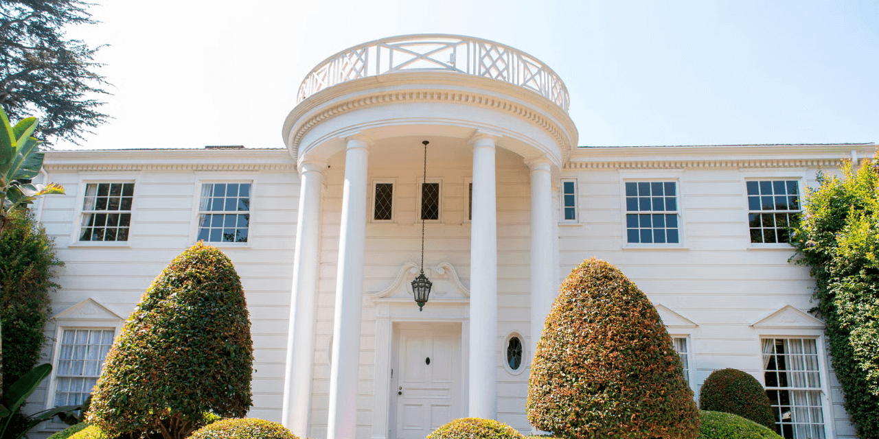 a large white estate with columns and hedges from the fresh prince of bel-air
