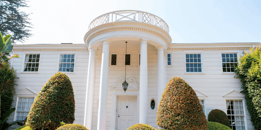 a large white estate with columns and hedges from the fresh prince of bel-air