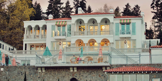 Italian-style lakefront mansion with white exterior and pink and teal accents