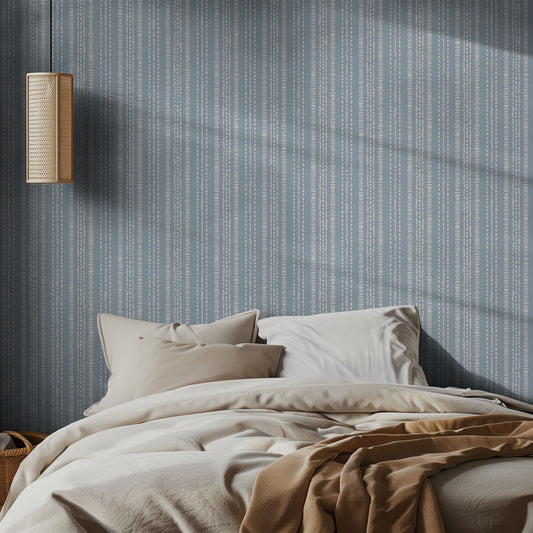 Bedroom with blue and white striped wallpaper, bed with beige bedding, and wall-mounted light fixture.