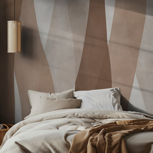 Bed with beige bedding against a wall with abstract brown and beige stripes mural, featuring a lamp on the wall.