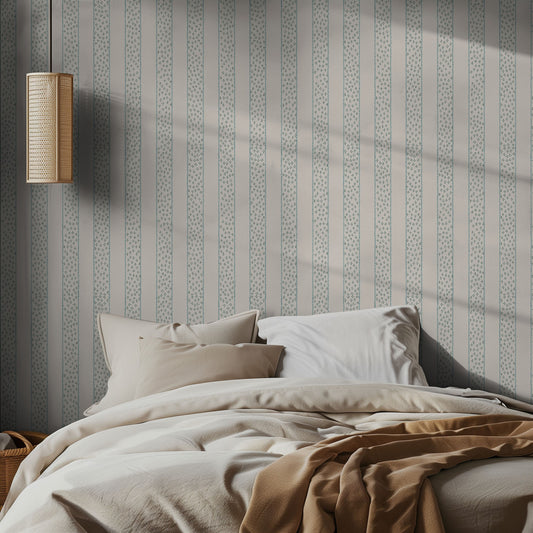 Bedroom with light striped wallpaper, neutral bed, and lamp.