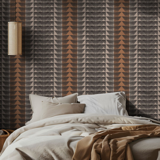Bedroom with orange, beige, and black geometric patterned wallpaper and soft neutral bedding.