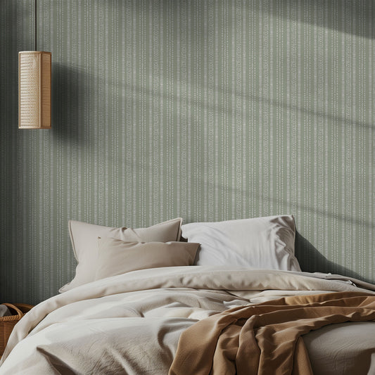 Bedroom with green striped wallpaper, wooden lamp, and beige bedding.