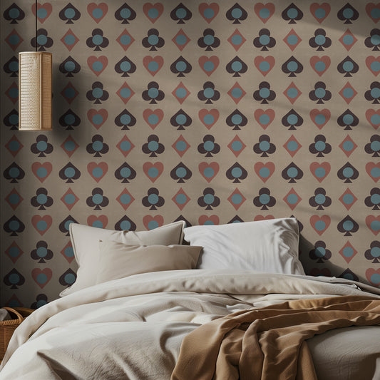 Bedroom with playing card patterned wallpaper featuring playing card suits and a bed with beige bedding.