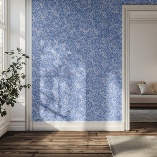 Hallway with a wall featuring a blue and white, floral geometric wallpaper pattern, a plant, and a sofa in the background.