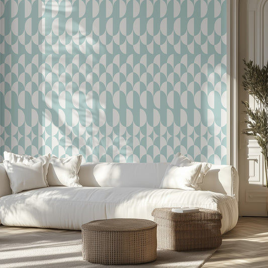 Aqua and white wavy geometric wallpaper pattern in a living room setting with a boho neutral white couch and wicker ottomans. 