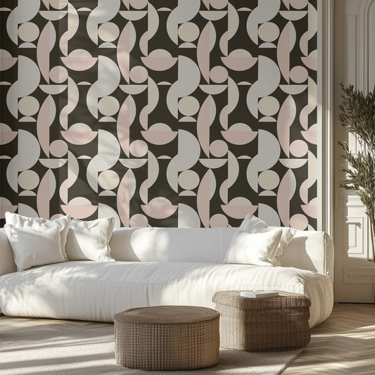 Modern living room with geometric wallpaper pattern with abstract shapes in pink, beige, and gray. A neutral white couch and two wicker ottomans.