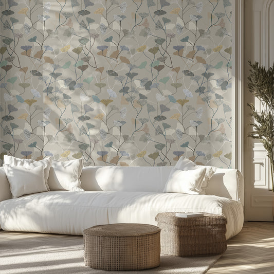 Modern living room with neutral earthy leaf patterned wallpaper, a white couch, and two wicker ottomans.
