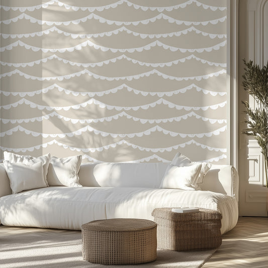 Modern living room with a white sofa, beige wallpaper with white scalloped garland, and wicker ottomans.