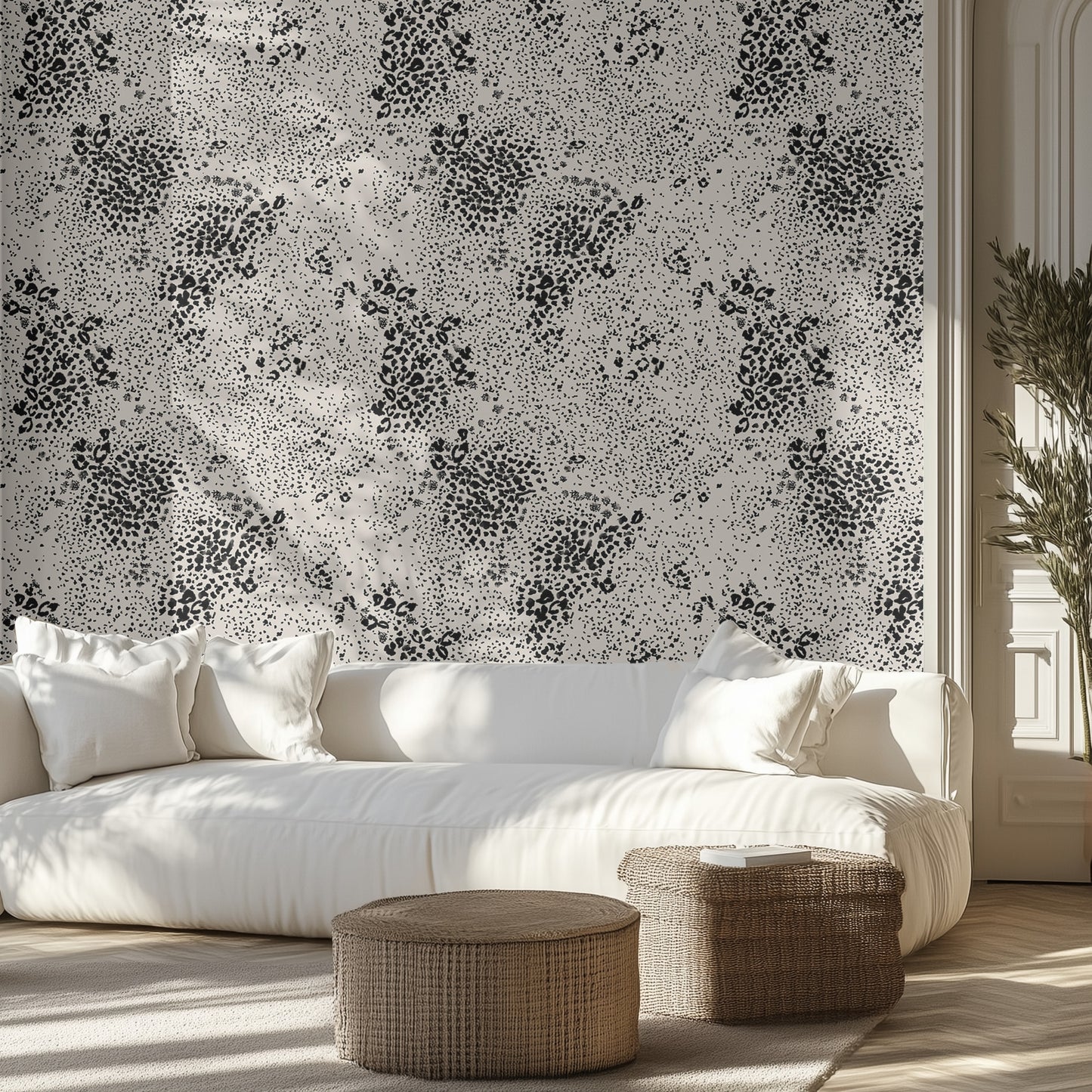 Modern living room with white sofa, black and gray chetah patterned wall, and wicker ottomans.