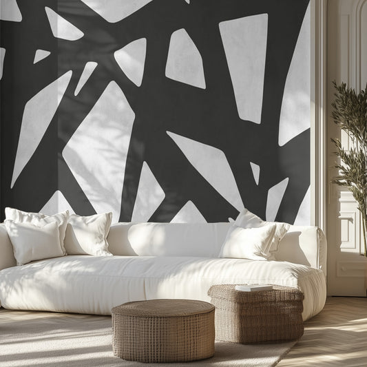 Modern living room with abstract black and white wall design, white sofa, and wicker ottomans.