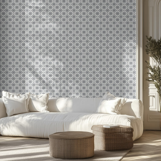 Living room with a white sofa, black and white star burst patterned wallpaper, and wicker ottomans.