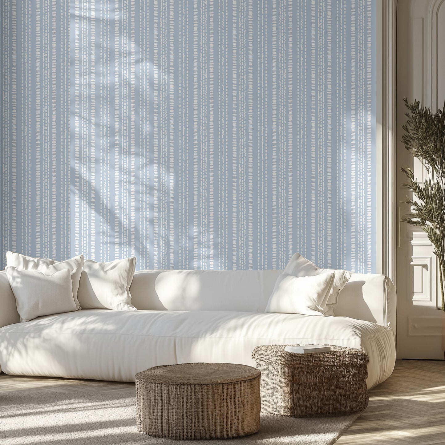 Living room with white sofa, a wall with wallpaper pattern with white dashed stripes on a blue background, and wicker ottomans.