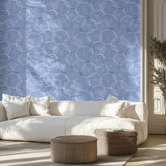 Modern living room with a white sofa, decorative pillows, and a blue and white floral patterned wall.