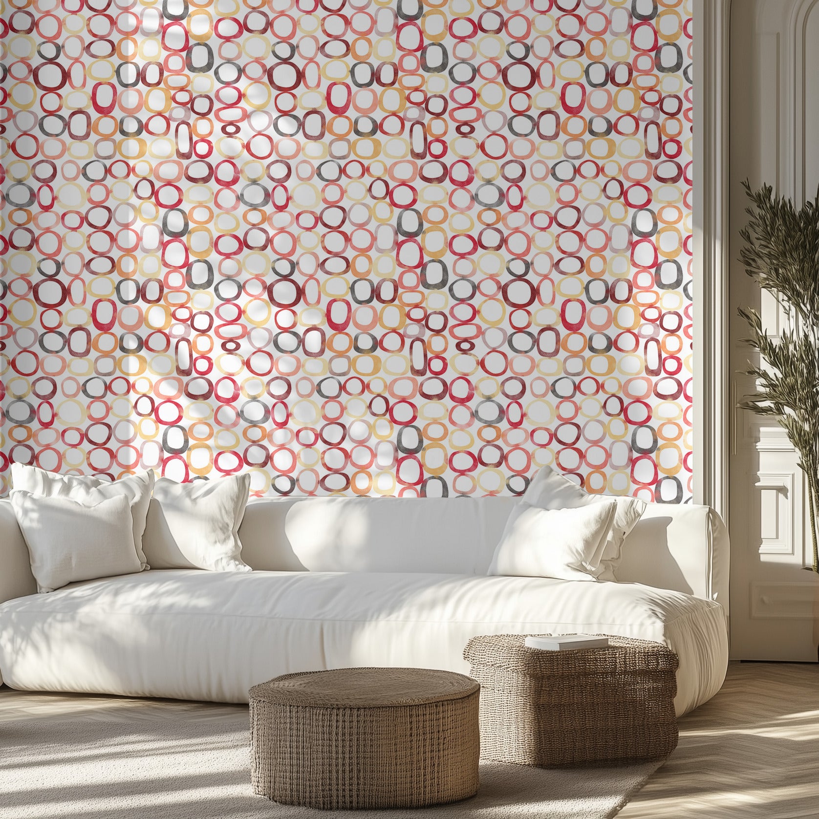 Modern living room with a white sofa,  patterned wall of watercolor rings, and wicker ottomans.