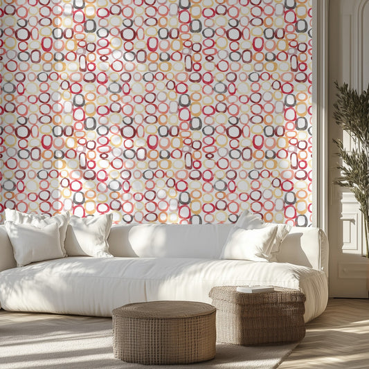 Modern living room with a white sofa,  patterned wall of watercolor rings, and wicker ottomans.
