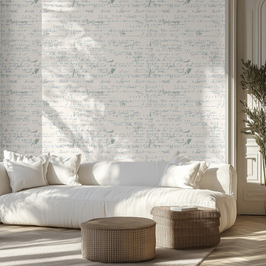 Living room with white sofa, blue vintage handwritten patterned wallpaper, and wicker ottomans.