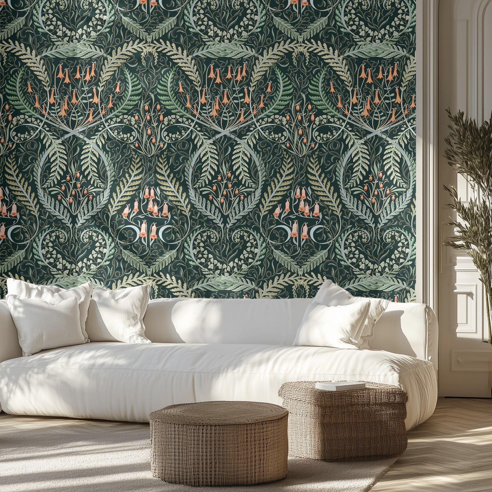 Living room with wallpaper featuring an ornate botanical pattern of orange bell flowers, ferns, on a dark green background. A white couch and two wicker ottomans.