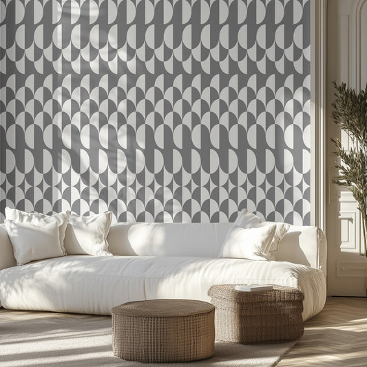 Living room with a white sofa, white and gray geometric patterned wall, and wicker ottomans.