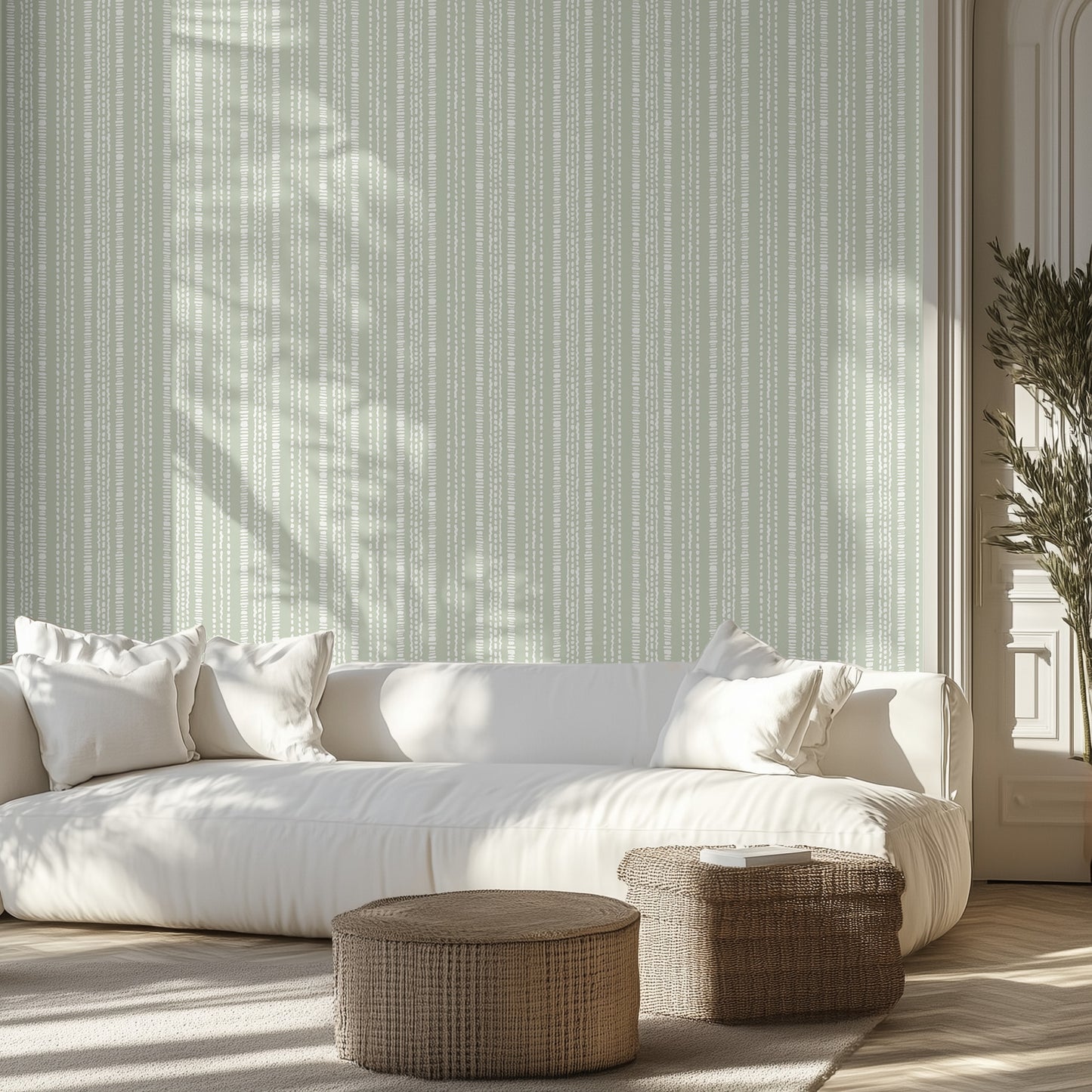 Living room with dotted striped wallpaper, white sofa, and wicker ottomans.