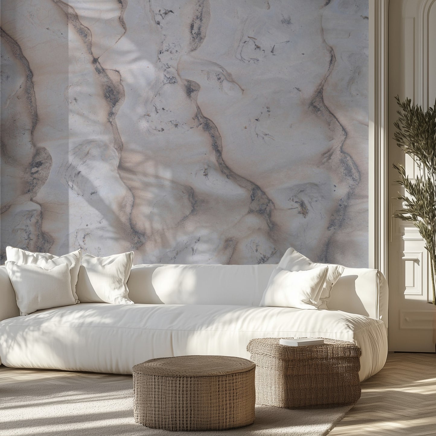 Modern living room with a white sofa, white marble wall, and wicker ottomans.