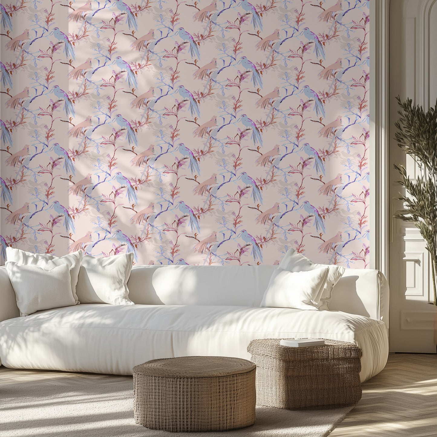 Modern living room with a white sofa, soft pink and blue bird patterned wall, and wicker ottomans.