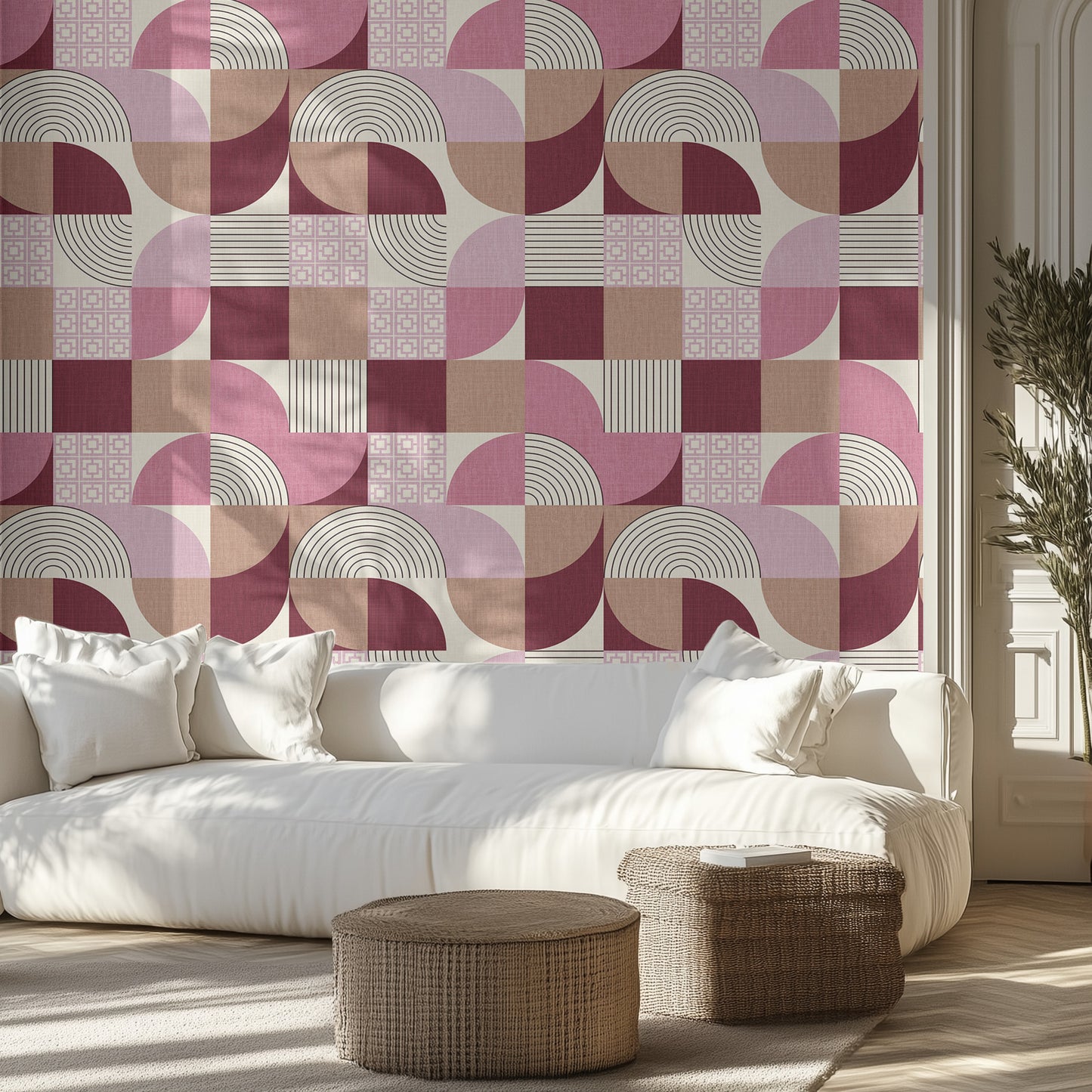 Living room with a pink and beige geometric patterned wall, white sofa, and wicker ottomans.