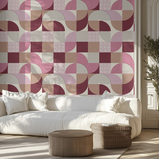 Living room with a pink and beige geometric patterned wall, white sofa, and wicker ottomans.