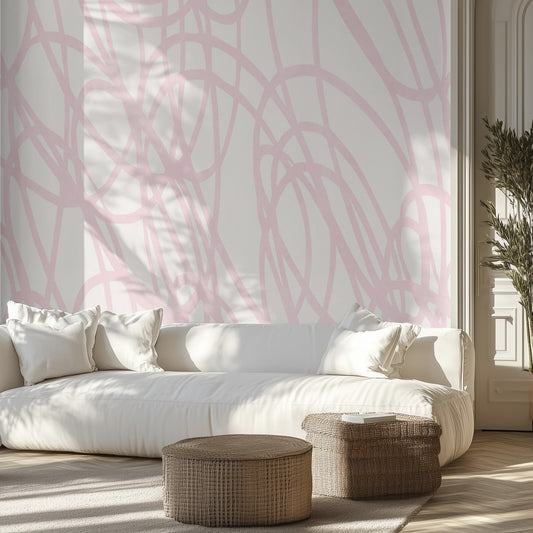 Living room with white sofa, pink abstract lines wall mural, and wicker ottomans.