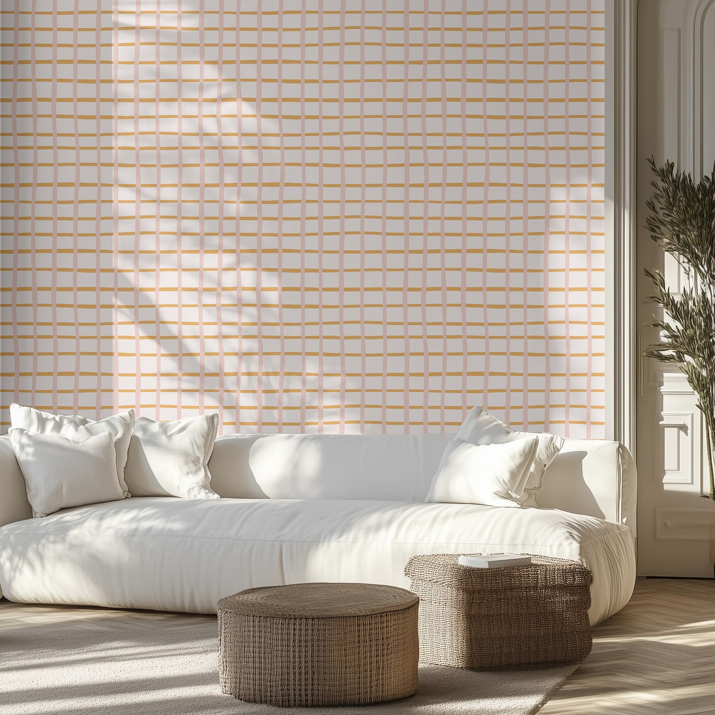 Modern living room with a white sofa, pink and orange geometric patterned wall, and wicker ottomans.
