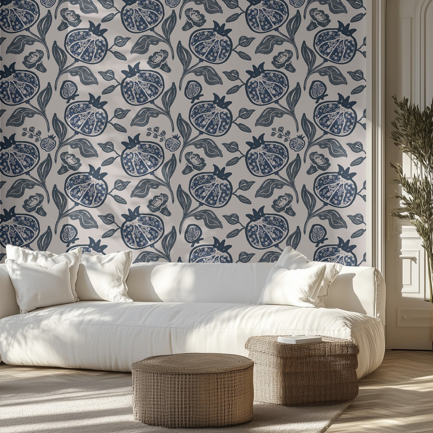 Living room with white sofa, blue pomegranate patterned wallpaper, and decorative ottomans.