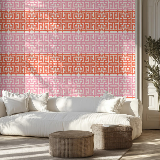 Living room with a white sofa, pink and red geometric patterned wall, and wicker ottomans. 