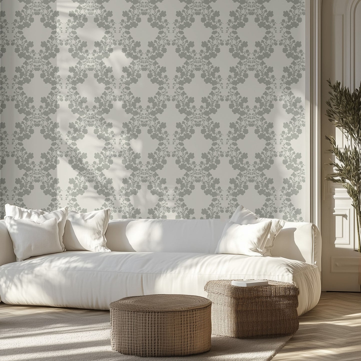 Living room with white sofa, sage floral patterned wallpaper, and wicker ottomans.
