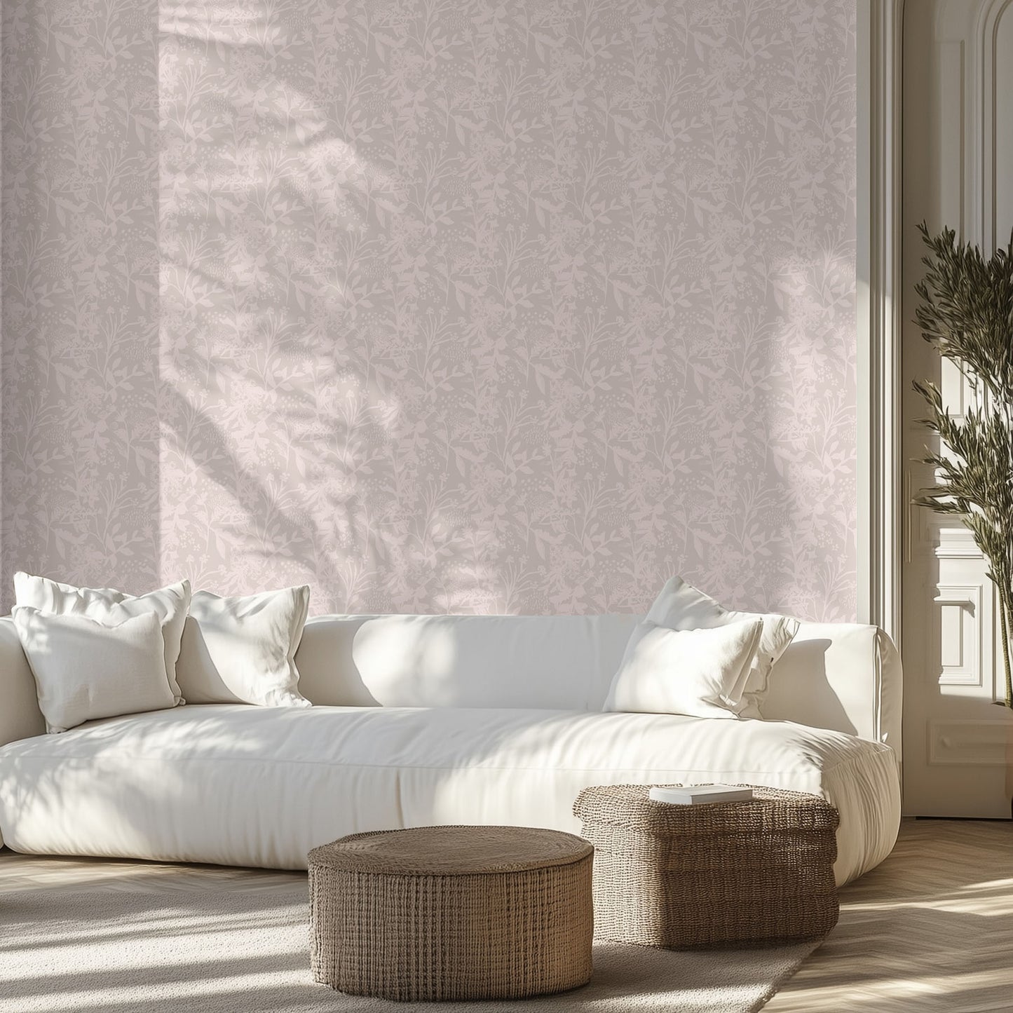 Modern living room with a white sofa, soft pink and mauve floral patterned wall, and wicker ottomans.