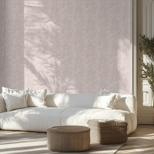 Modern living room with a white sofa, soft pink and mauve floral patterned wall, and wicker ottomans.