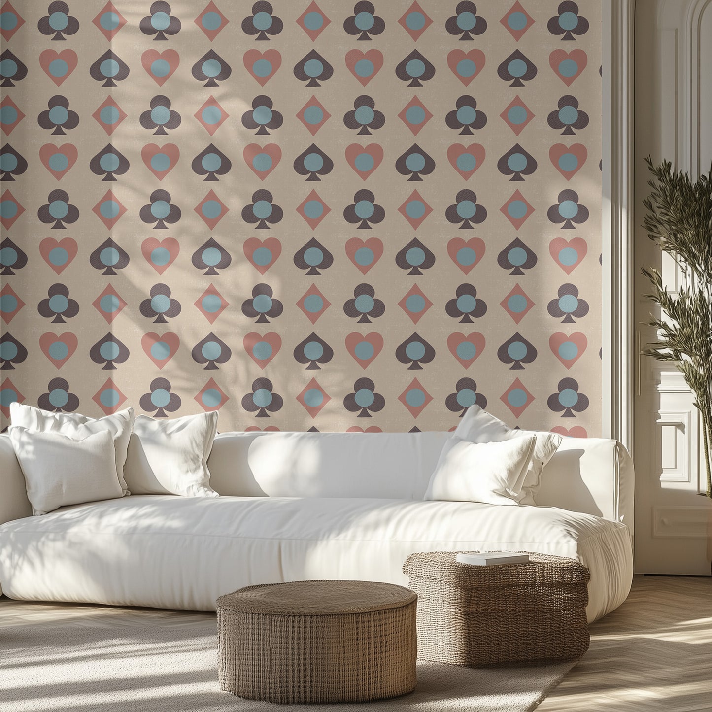 Modern living room with a white sofa, wicker ottomans, and playing card patterned, textured wall.