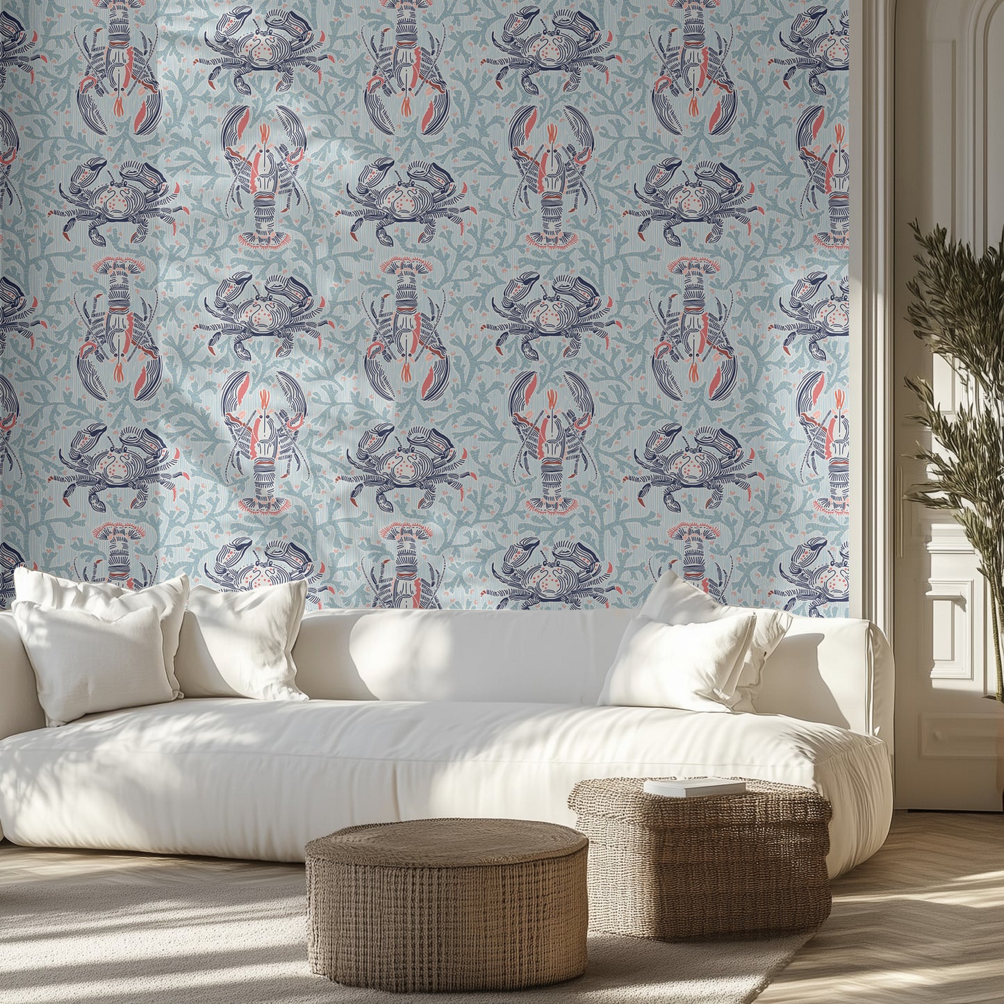 Living room with a white sofa, lobster and crab patterned wall in blue and teal, and wicker ottomans.