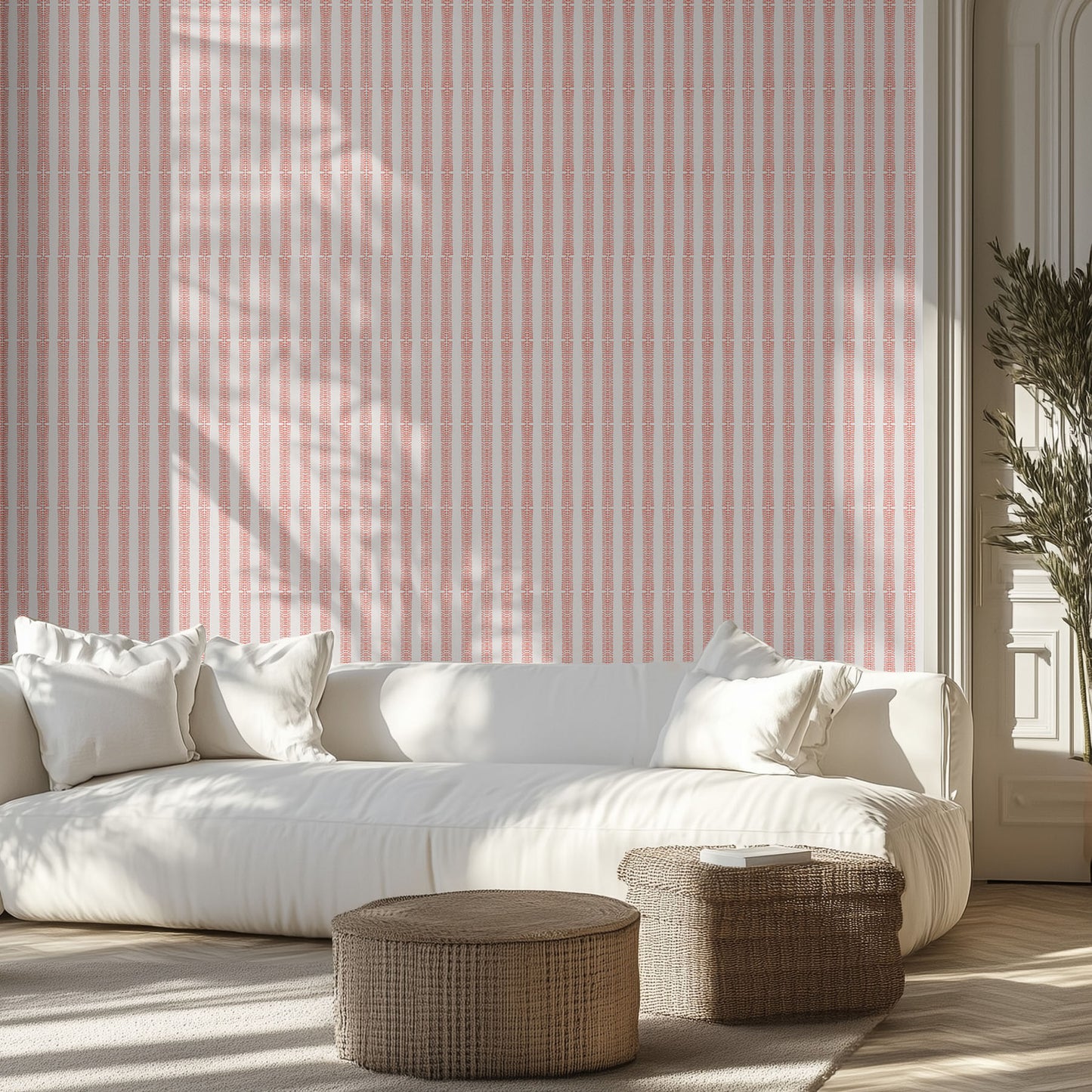 Living room with white sofa, patterned pink and white striped wallpaper, and wicker ottomans.