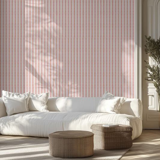 Living room with white sofa, patterned pink and white striped wallpaper, and wicker ottomans.