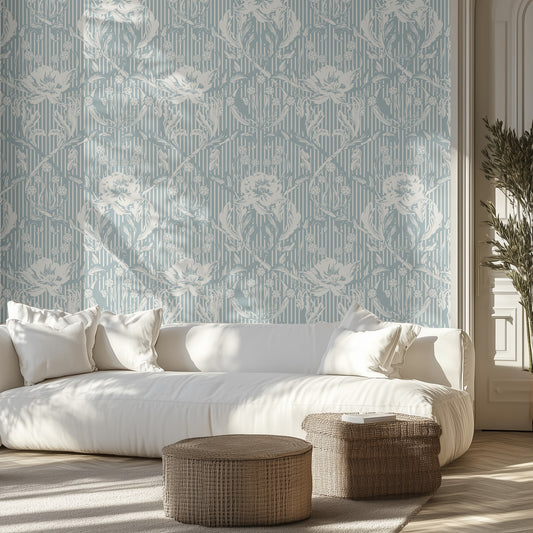 Living room with a white sofa, light teal floral and stripe patterned wallpaper, and wicker ottomans.