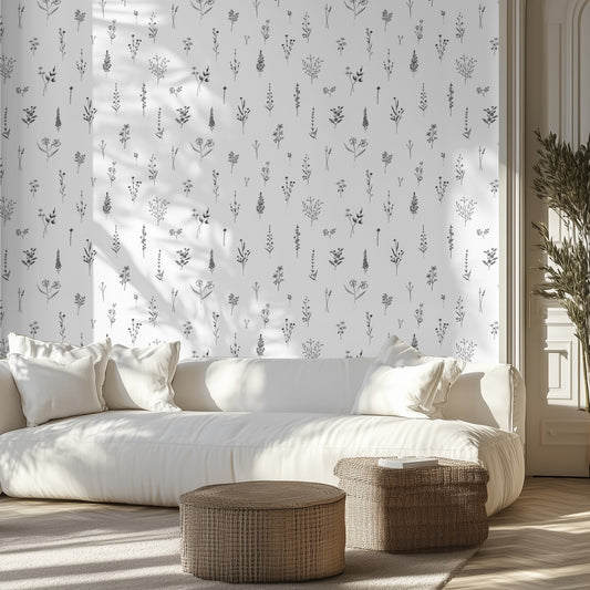 Living room with white sofa, patterned black and white line drawings on wallpaper, and wicker ottomans.